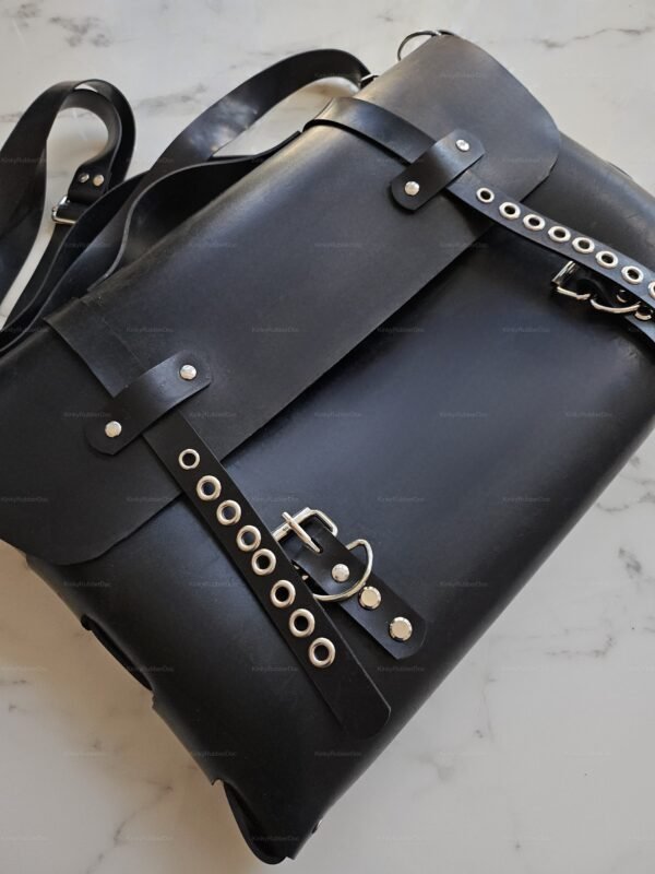 Sleek black unisex latex briefcase-style bag with rivet and buckle details on a marble surface.